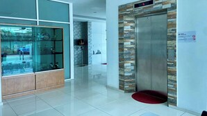 A modern lobby with a glass display case, a red carpet, and an elevator with a stone facade. - Hotel Dlima Inn Plaza Mahkota Melaka (Malacca City)
