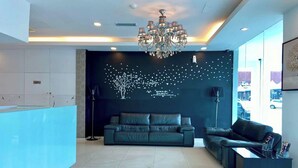 A modern reception area with a reception desk, a dark-colored sofa, a coffee table, and a chandelier. - Hotel Dlima Inn Plaza Mahkota Melaka (Malacca City)