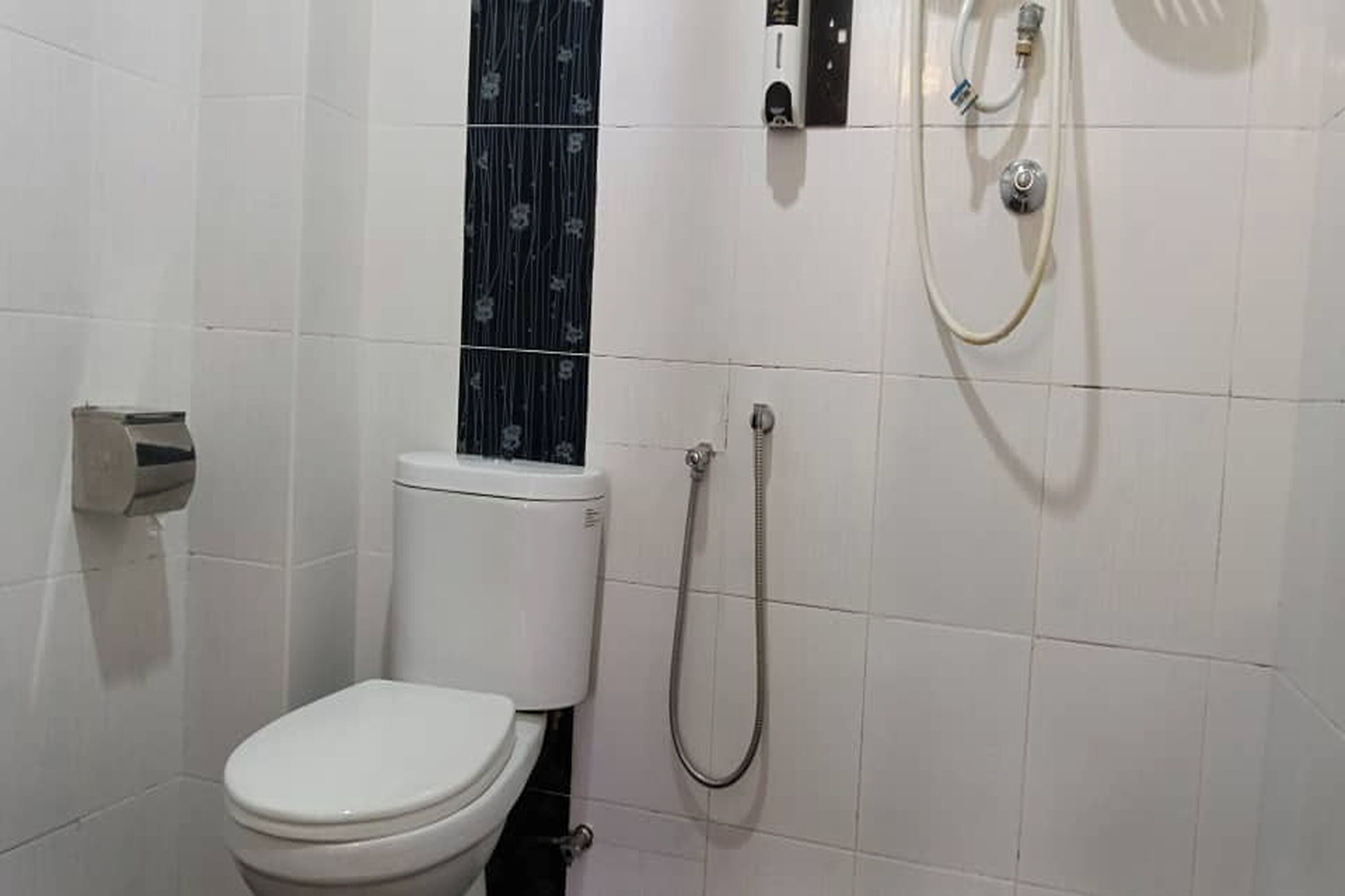 Baño pequeño y funcional con inodoro, ducha y secamanos.