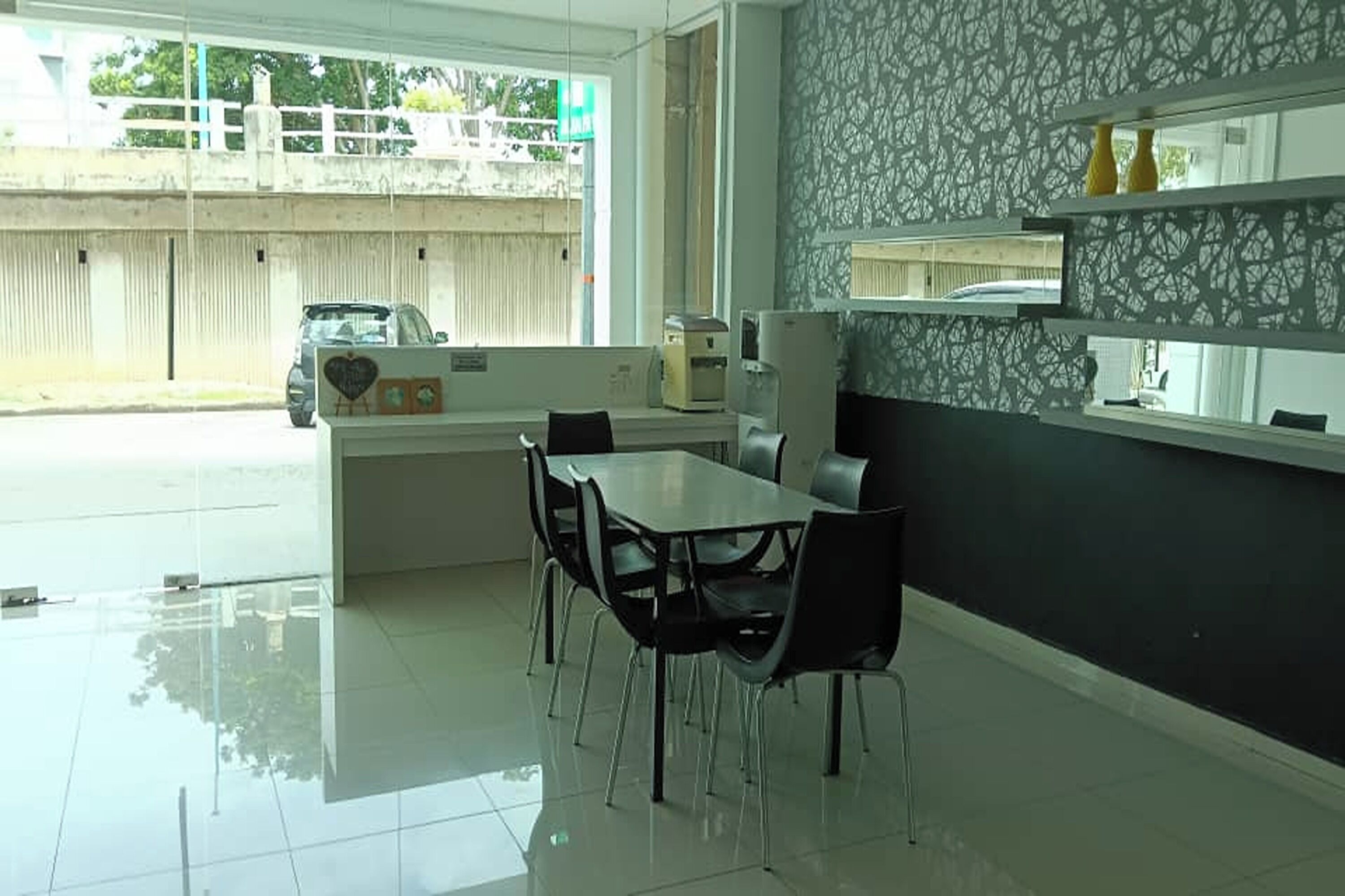 A modern dining area with a glass partition, a white table, and black chairs.