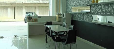 A modern dining area with a glass partition, a white table, and black chairs.
