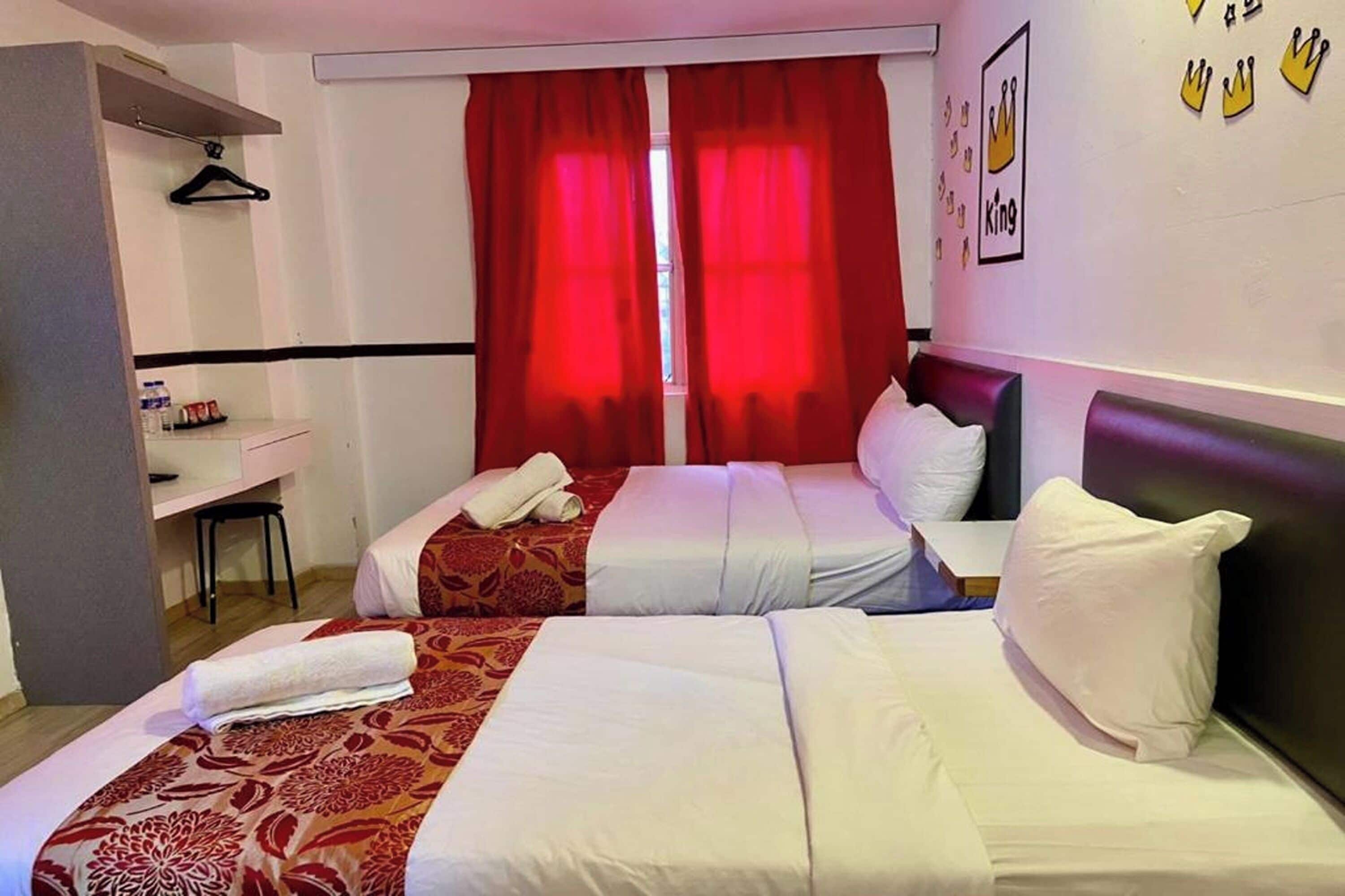 Ein Hotelzimmer mit zwei Betten, einem Schreibtisch und einem Sessel.
