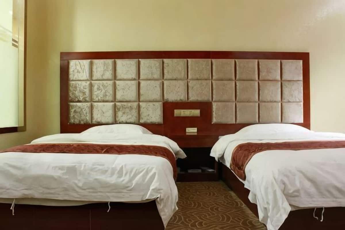 A hotel room with two beds, a wooden headboard, and a patterned carpet.