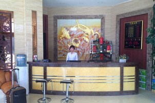 A reception area with a receptionist, a reception desk, a bar area, and a decorative wall with a floral pattern.