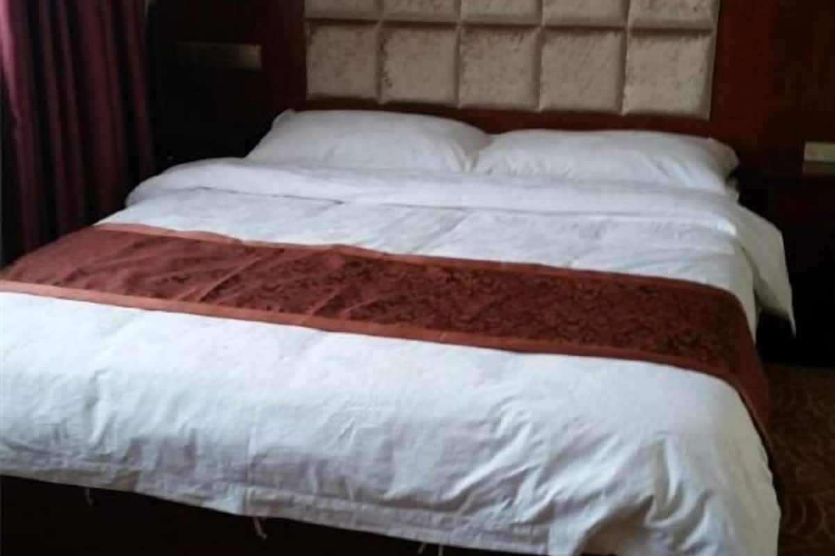 A hotel room with a bed, a headboard, and a nightstand.