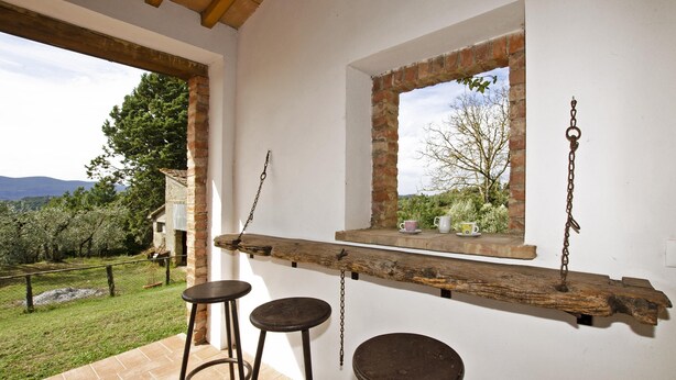 A rustic interior with a wooden beam shelf, two stools, and a window overlooking a garden. - Fontesecca in Citt Della Pieve (Citta della Pieve)
