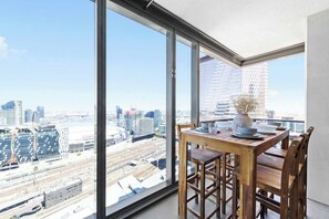 Un appartement situé dans un immeuble de grande hauteur, doté d’une grande baie vitrée offrant une vue sur la ville.