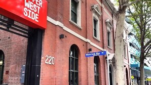 Un edificio de ladrillo rojo con un letrero que dice "Upper West Side" y una señal de calle azul para "Watertank Way".