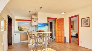 Une cuisine spacieuse avec un coin repas, un téléviseur et une vue sur la plage.