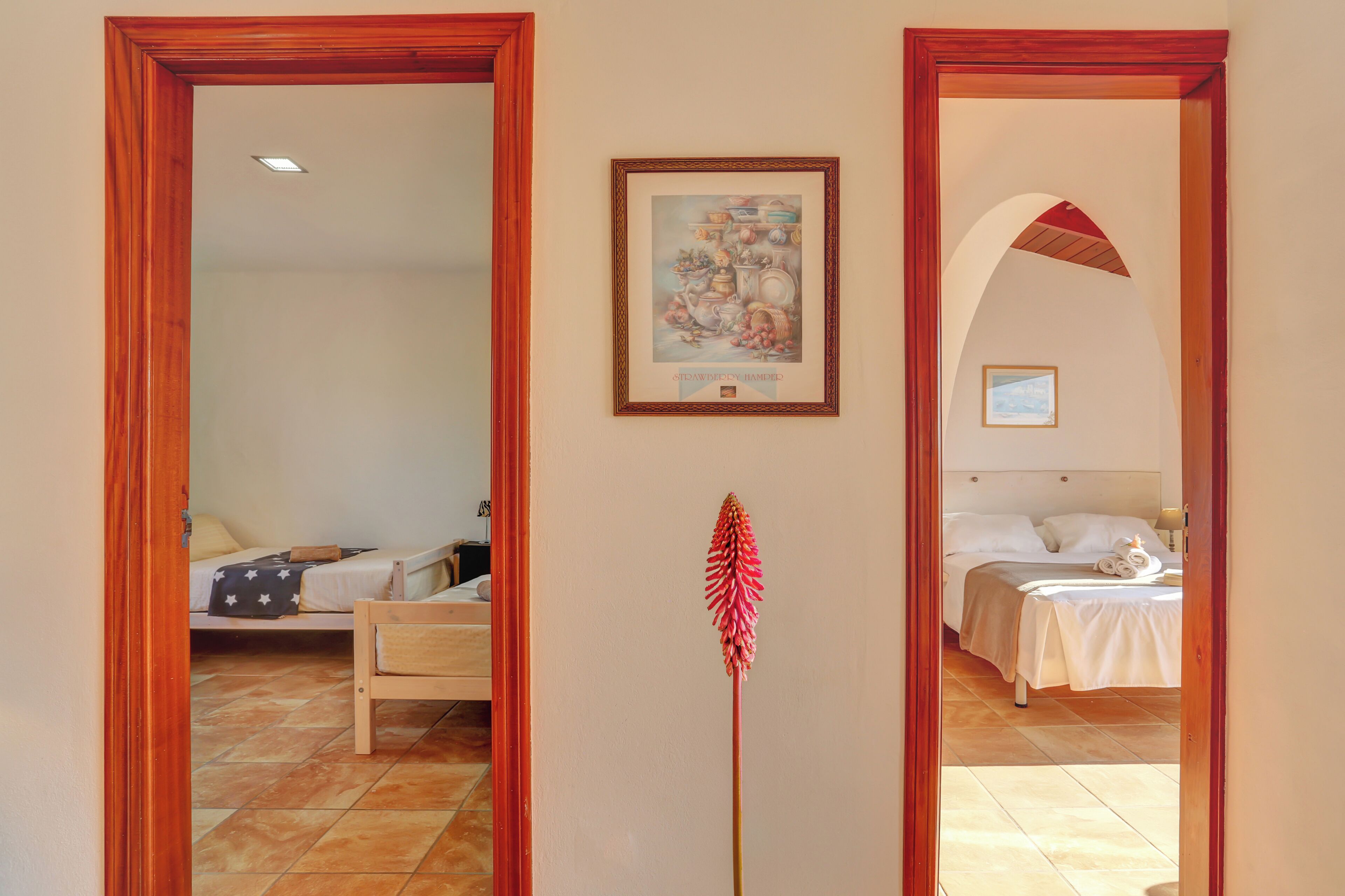 Habitación de hotel con cama, mesita de noche, un cuadro enmarcado en la pared y un espejo que refleja la habitación.