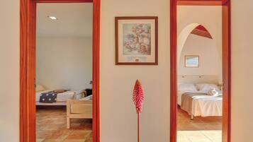 Habitación de hotel con cama, mesita de noche, un cuadro enmarcado en la pared y un espejo que refleja la habitación.