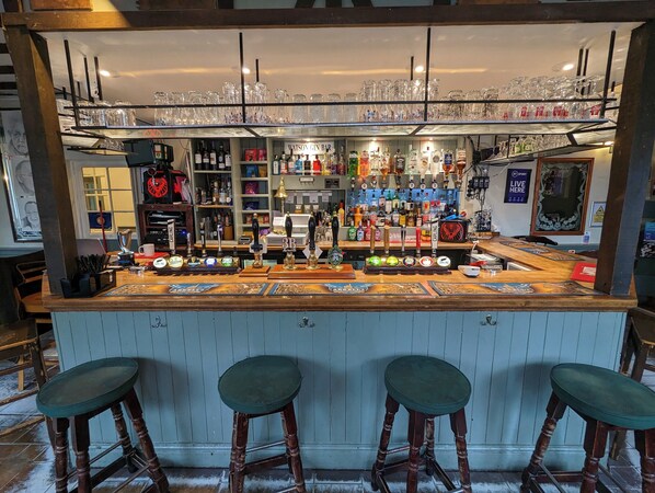 A bar area with stools, a variety of bottles, glasses, and a sign reading "Watson Gin Bar". - The Bear  (Marlborough)