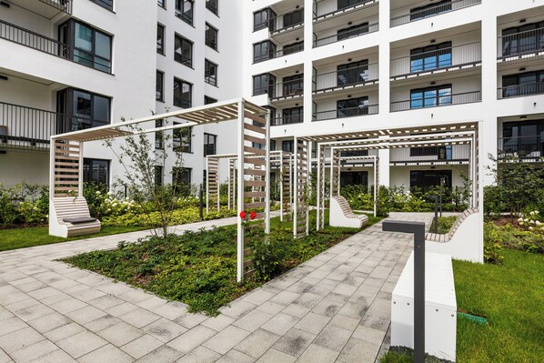 Residents enjoy a serene garden with a variety of plants and a shaded pergola.