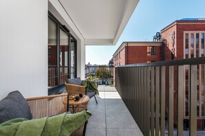 Relax in a comfortable seating area with a wicker chair and cushioned bench, taking in the city view.