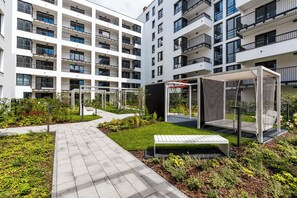 Enjoy the serene outdoor space with a paved walkway, grassy area, and seating bench amidst lush greenery.