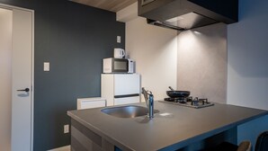 A compact kitchen with a sink, stove, microwave, and a small refrigerator. - BON Osaka West (Osaka)