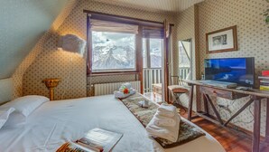A bedroom with a bed, a desk with a TV, a window with a mountain view, and a radiator. - La Stella Alpina in Sestriere (Sestriere)