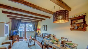 A cozy living room with a wooden ceiling, a dining table set with plates and glasses, and a television on a stand. - La Stella Alpina in Sestriere (Sestriere)