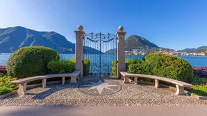 Un banco de piedra y una puerta que dan a una vista panorámica de un lago y montañas.