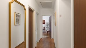 Un pasillo con suelo de madera, paredes blancas y puertas que dan a otras habitaciones.