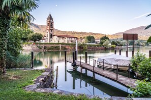 A serene lakeside scene with a church, dock, and calm water. - Al Pontile Di Caslano (Caslano)