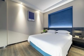 A modern hotel room with a large bed, a nightstand with a lamp, a framed picture on the wall, and a blue accent wall. - Yiman Hotel(Ningbo Passenger Transport Center) (Ningbo)