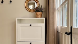 A white cabinet with three drawers, a wicker basket on top, a gold-framed mirror, and a wicker basket on the floor. - Holidays in the old vicarage in the Lüneburg Heath
stylish
fireplace
terrace (Steinhorst)