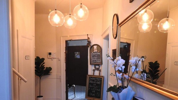 A hallway with a wooden floor, a blackboard with handwritten notes, a mirror, and a plant. - 2-person Room in a Hotel in Tranekaer (Tranekaer)