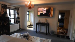 A bedroom with a bed, a TV, a chandelier, and a small table with busts. - 2-person Room in a Hotel in Tranekaer (Tranekaer)