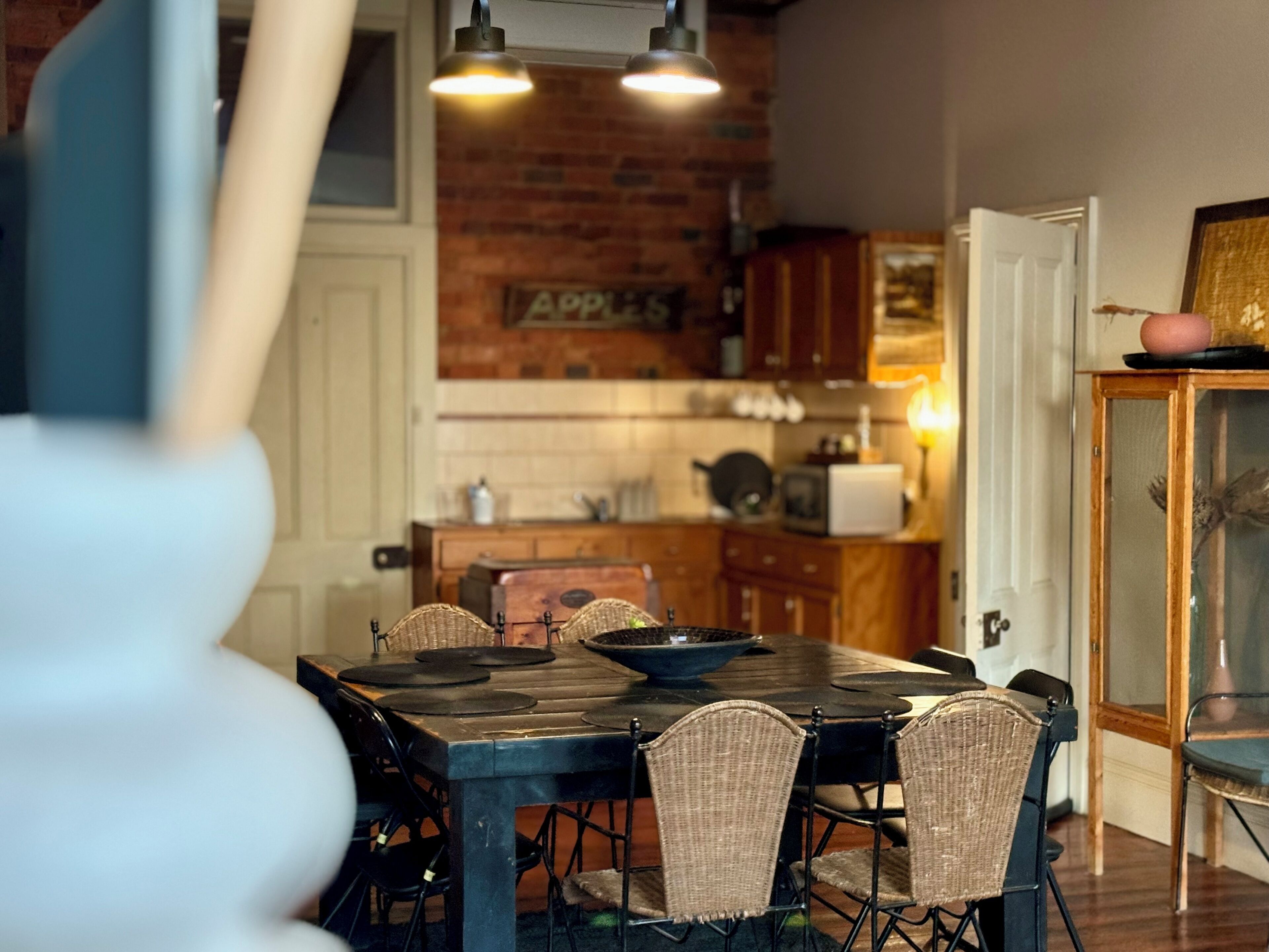 A dining area with a brick wall, wooden cabinets, and a table with chairs.