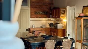 A dining area with a brick wall, wooden cabinets, and a table with chairs.