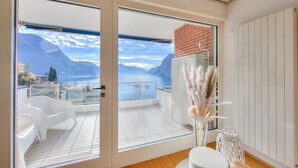 A modern room with a balcony overlooking a lake and mountains.