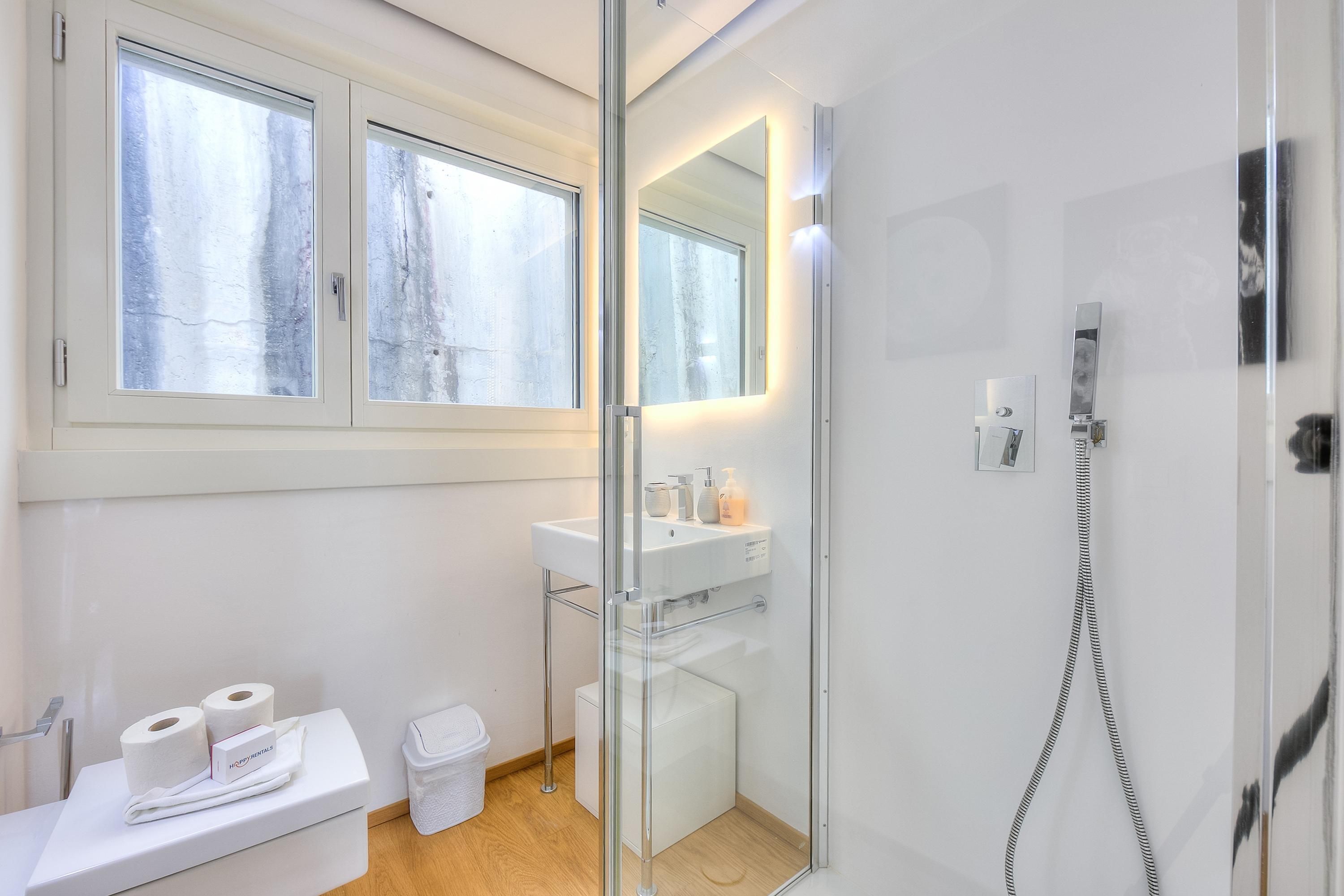 A modern bathroom with a glass shower enclosure, a white sink, and a toilet.