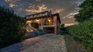 Un bâtiment en pierre doté d’un balcon et de nombreuses fenêtres, entouré de verdure.