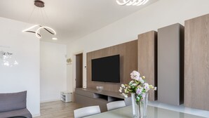 Ein modernes Wohnzimmer mit Flachbildfernseher, einem Glastisch und einer Couch.