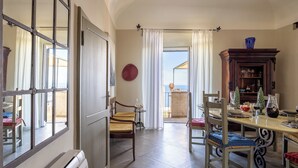 A dining area with a table, chairs, and a view to the outside. - Sunset Populonia by Geco Vacation Rentals (Piombino)