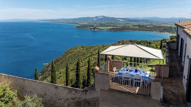 A terrace with a table and chairs overlooking a coastal landscape. - Sunset Populonia by Geco Vacation Rentals (Piombino)