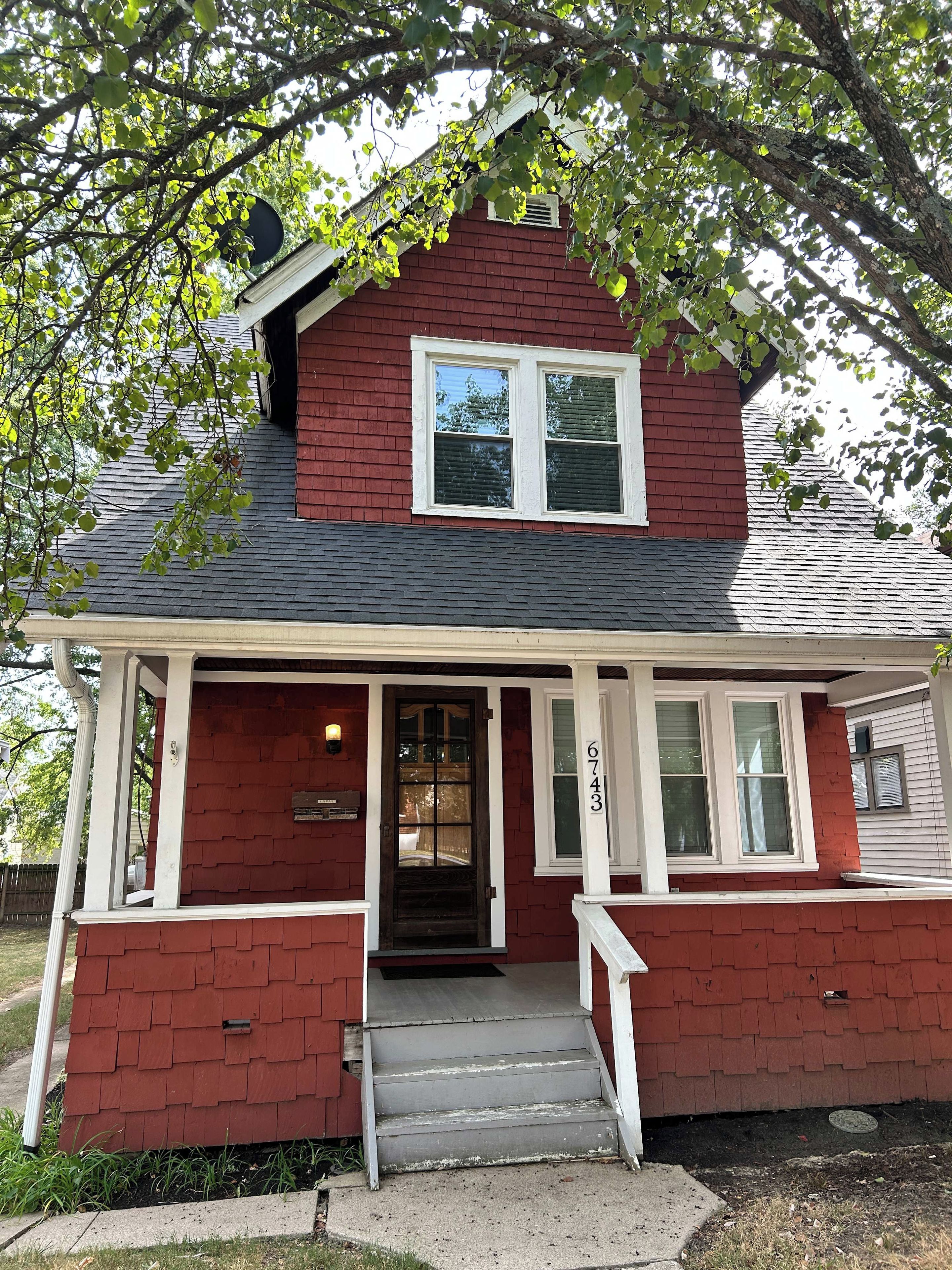 A red house with a front porch, a two-story structure, and a visible address number.