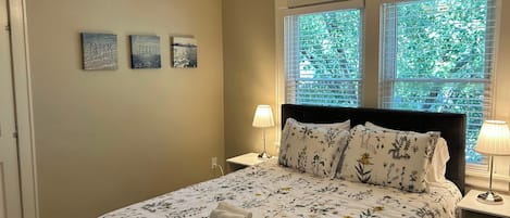 A bedroom with a bed, two nightstands, a ceiling fan, and three wall art pieces.