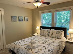 A bedroom with a bed, two nightstands, a ceiling fan, and three wall art pieces.