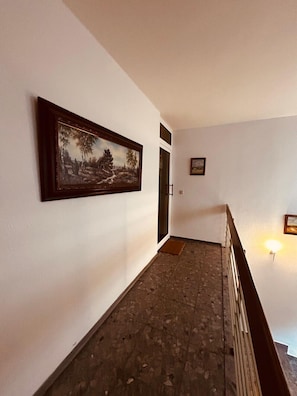 A hallway with a framed painting, a door, and a light fixture.