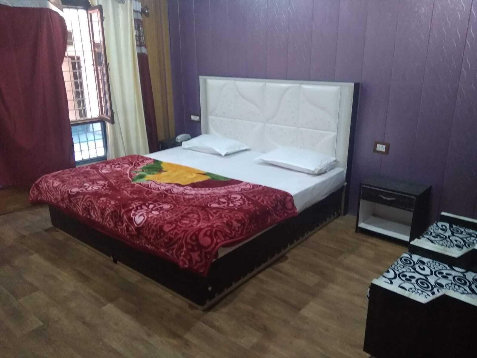 A bedroom with a bed, a nightstand, and a window with curtains.