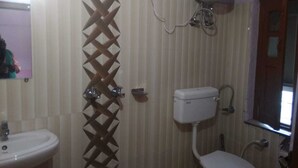A bathroom with a toilet, sink, and shower area. - Hotel Grand Kailash (Joshimath)