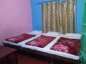 Uma cama de solteiro com roupa de cama florida, uma mesa de cabeceira e uma cortina estampada com flores.