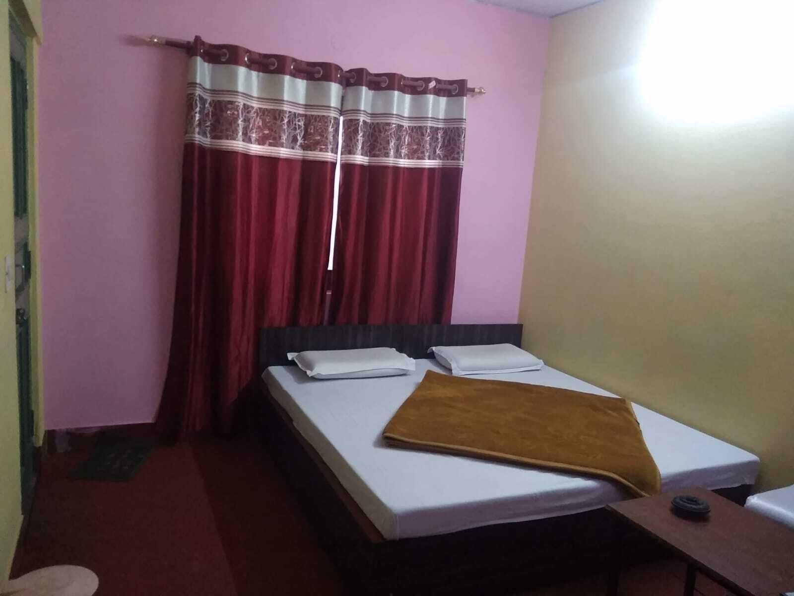 Una habitación con cama, una mesita y una ventana con cortinas.