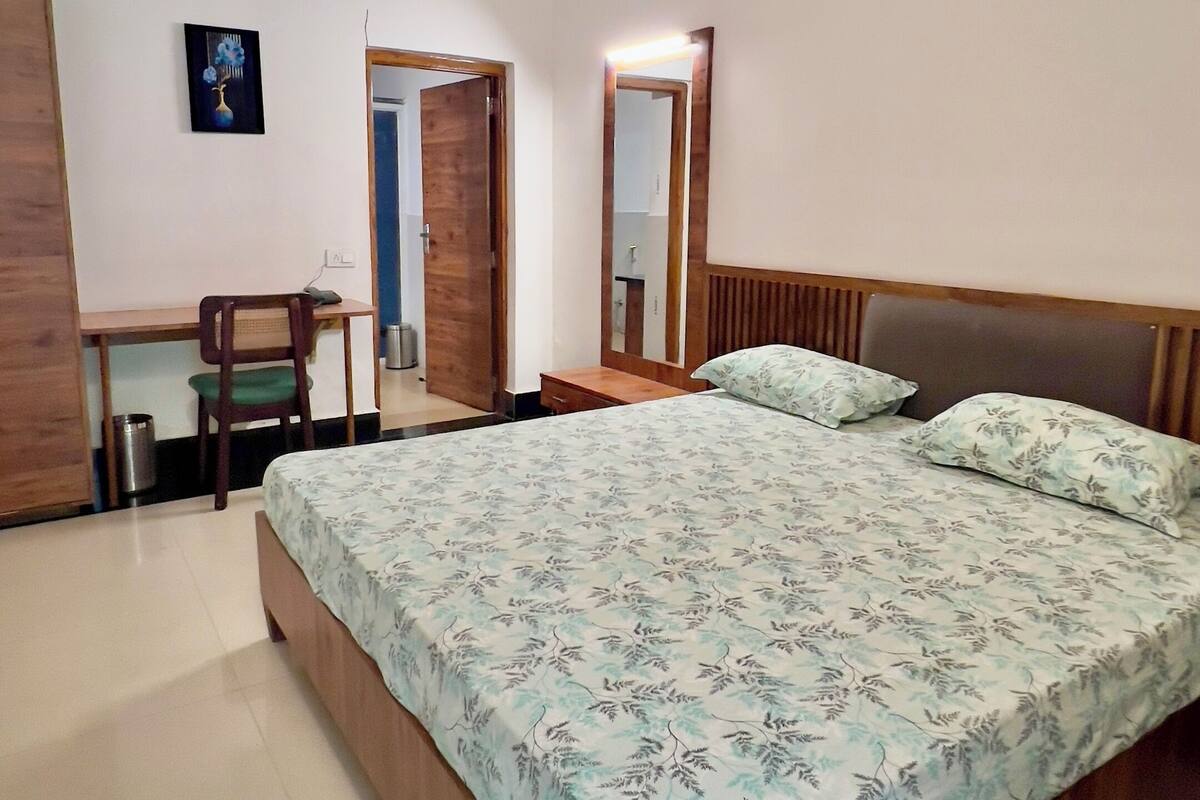 A bedroom with a bed, a desk, a chair, an air conditioner, and a ceiling fan.