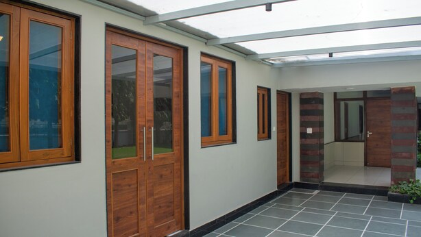 A corridor with wooden doors and a tiled floor, leading to a room with a glass ceiling. - Villa Vilas (Udaipur)