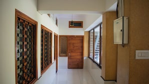 A hallway with tiled flooring, wooden doors, and a wall-mounted electrical box. - Villa Vilas (Udaipur)