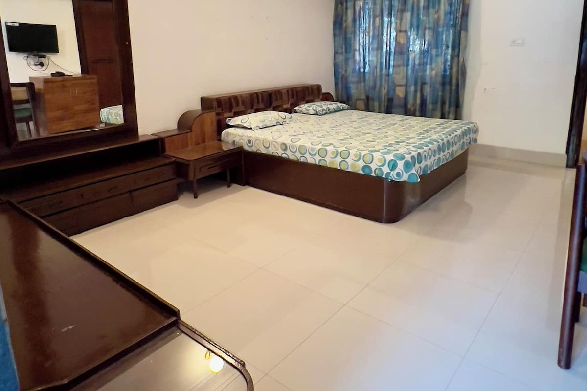 A bedroom with a bed, a dresser, a mirror, a ceiling fan, and an air conditioning unit.