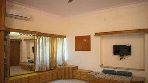 A bedroom with a large mirror, a bed, a TV, and a built-in bench. - Villa Vilas (Udaipur)